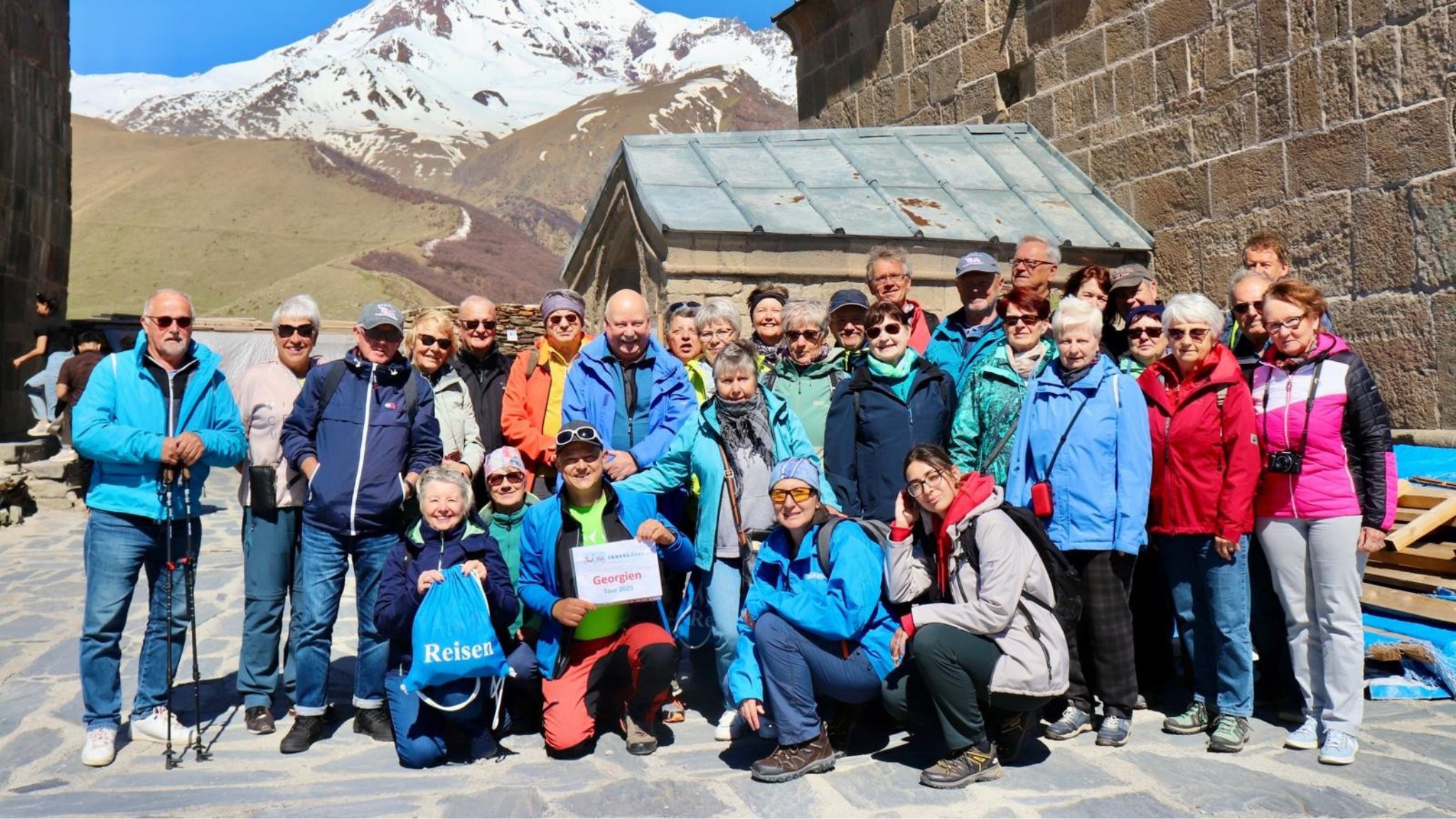 Locate Georgia travel group at Gergeti Trinity Church with Mount Kazbek behind